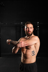 Fototapeta na wymiar Portrait of handsome muscular man stretching before training in gym. Routine workout for physical and mental health.