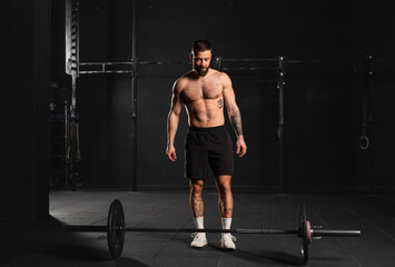 Strong man preparing for barbell lift, overhead squat, standing by barbell. Routine workout for...