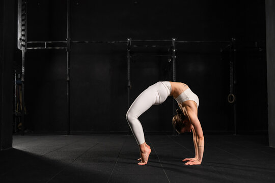 Woman doing acroyoga alone, solo. Flexibile woman focusing on yoga and acrobatics, preparing for partner exercises.