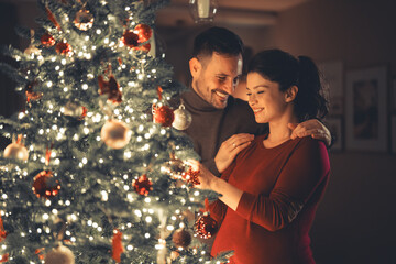 A lovely happy young adult married couple enjoying each others company and decorating the Christmas...
