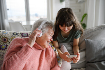 Cute girl showing funny video to gradmother. Portrait of an elderly woman spending time with granddaughter.