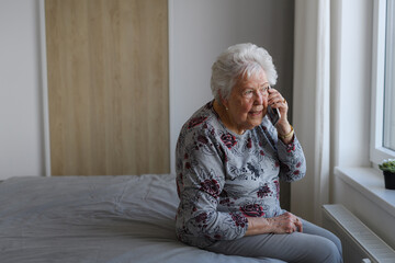 Senior woman making phone call, spending time alone in her apartment. Concept of loneliness and...