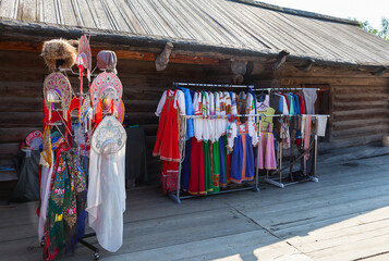 Russian folk costumes, sundresses, hats, kokoshniks in сourtyard of old house in Architectural and ethnographic open-air museum Siberian Taltsy village