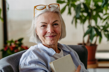Beautiful mature woman reading book, feeling cozy and happy. Weekend activity for older woman, relaxing at home.