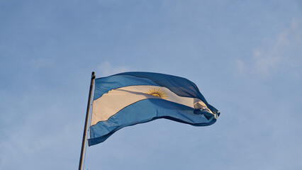 Details of an Argentine flag on a blue sky.