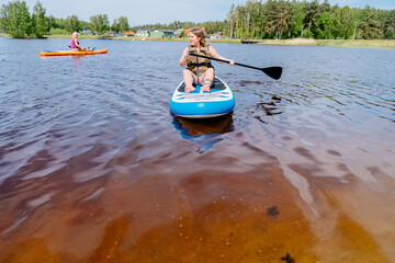 A woman is paddling a board in a lake surrounded by water and sky