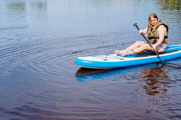 A woman on a paddle board in water holding a paddle