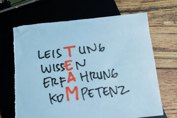 Concept of Learning language - German. Leistung, Wissen, Erfahrung, Kompetenz it means Performance, knowledge, experience, competence written on sticky notes. German language isolated on Wooden Table