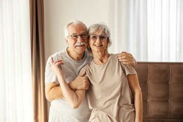 An affectionate senior couple standing in a bedroom at nursing home and hugging.