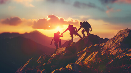 Climbing friends helping each other as a team reach the mountain peak at the sunset. People helping each other hike up a mountain. Giving a helping hand, Solidarity and active fit lifestyle concept.