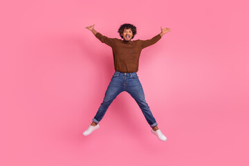 Photo of glad positive funky man wear trendy brown clothes jump up isolated on pink color background