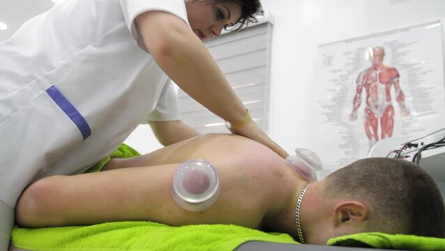 Footage of a physiotherapist doing a massage with a cupping massage therapy on a patients back