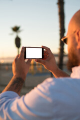 Close up view of male blogger holding smartphone with mock up screen using application for taking...