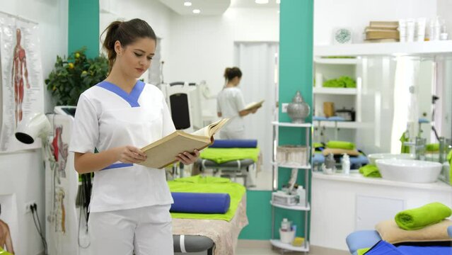 Footage of a young female physiotherapist reading professional literature, she looks straight into camera and smiles