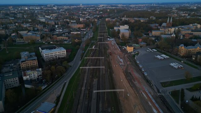 Enjoy a breathtaking aerial view of railway tracks and the urban cityscape, beautifully illuminated as dusk settles in