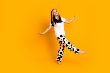 Full length photo of carefree adorable cute woman wear white stylish pajama have fun isolated on yellow color background