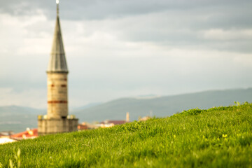 Minaret behind a grassy hill, blending nature and architecture beautifully.