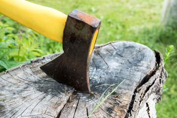 Ax with yellow handle stuck in old stump