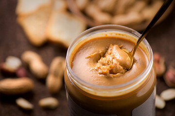 Peanut butter. Creamy smooth peanut butter in jar on a table. Spoon of natural organic vegan food....