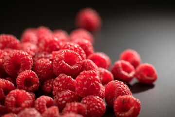 Raspberry fresh berries closeup, ripe fresh organic Raspberries over black background, macro shot. Harvest concept, border design