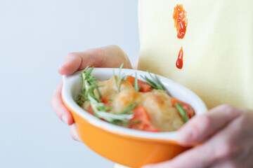 Close up drops tomato sauce or ketchup on yellow clothes. An unrecognizable woman holding a pastry...