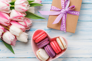 Pastel colorful tulips and vibrant macaroons fill a heart-shaped bowl