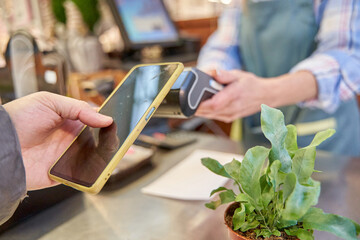 Iago via mobile phone. detail of the hand of an unrecognisable man paying in a shop with a contactless phone.