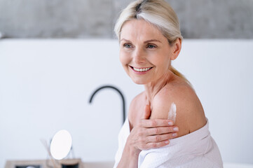 Senior woman applying soft cream after shower on skin