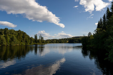 Serene lake, lush trees, blue sky with fluffy clouds