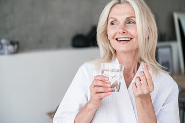 50s old woman taking capsule with Omega 3, nutrition concept