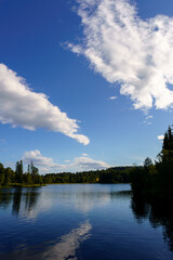 Serene lake, lush trees, blue sky with fluffy clouds
