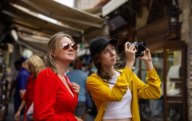 Two tourists take photos in a crowded tourist city.