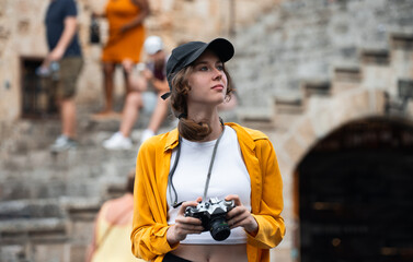 Girl with a vintage camera on the square among tourists.