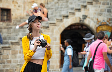 Girl with a vintage camera on the square among tourists.