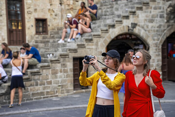 Two tourists take photos in a crowded tourist city.
