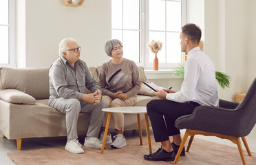 Young consultant, agent provides expert assistance to a senior client couple during home meeting....