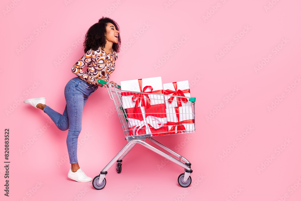 Poster Full length photo of shiny attractive lady dressed print shirt walking shopping cart choosing gifts isolated pink color background