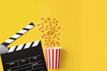 Popcorn caramel bucket and Cinema clapper board, crunchy sweet snack, movie theater treat,...