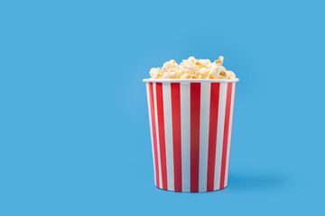Popcorn bucket, cinema treat, movie snack, striped pack,blue background