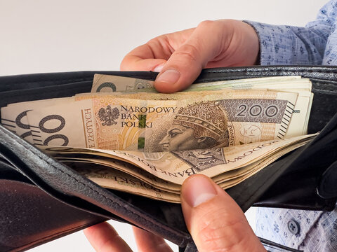  man takes Polish zlotys from his wallet. Man counting money pln