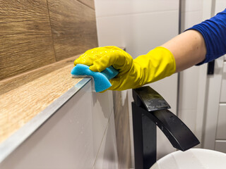 close up female hand in gloves cleaning bathroom furniture
