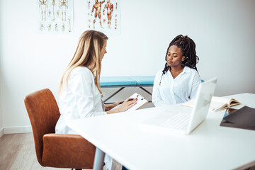 Female patient and doctor discussing test results in medical office. African American woman at a...