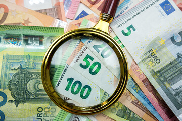 magnifying glass on different euro bills as background. Finance concept