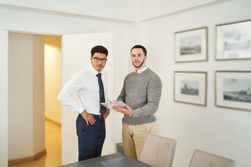 Two men are standing in front of a table with papers on it