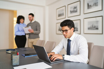 Obraz premium A man is typing on a laptop in front of a group of people