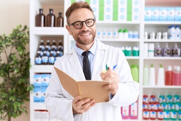 Middle age man pharmacist writing on notebook at pharmacy