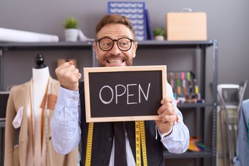 Middle age man with beard dressmaker designer holding open sign screaming proud, celebrating victory and success very excited with raised arms