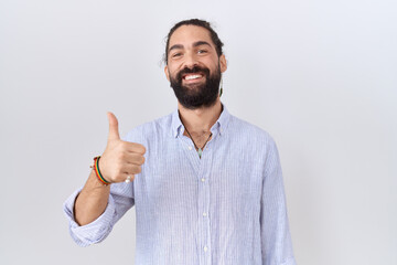 Hispanic man with beard wearing casual shirt doing happy thumbs up gesture with hand. approving expression looking at the camera showing success.