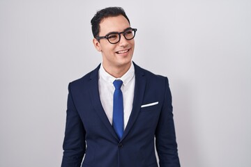 Young hispanic man wearing suit and tie looking away to side with smile on face, natural expression. laughing confident.