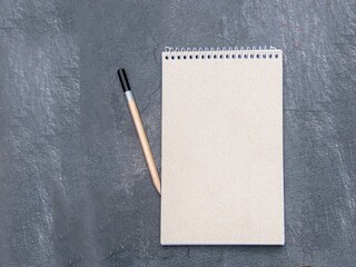 Top view of a open notebook with recycled paper with pencil on a slate background, school notebooks with a spiral spring, office notepad flat lay